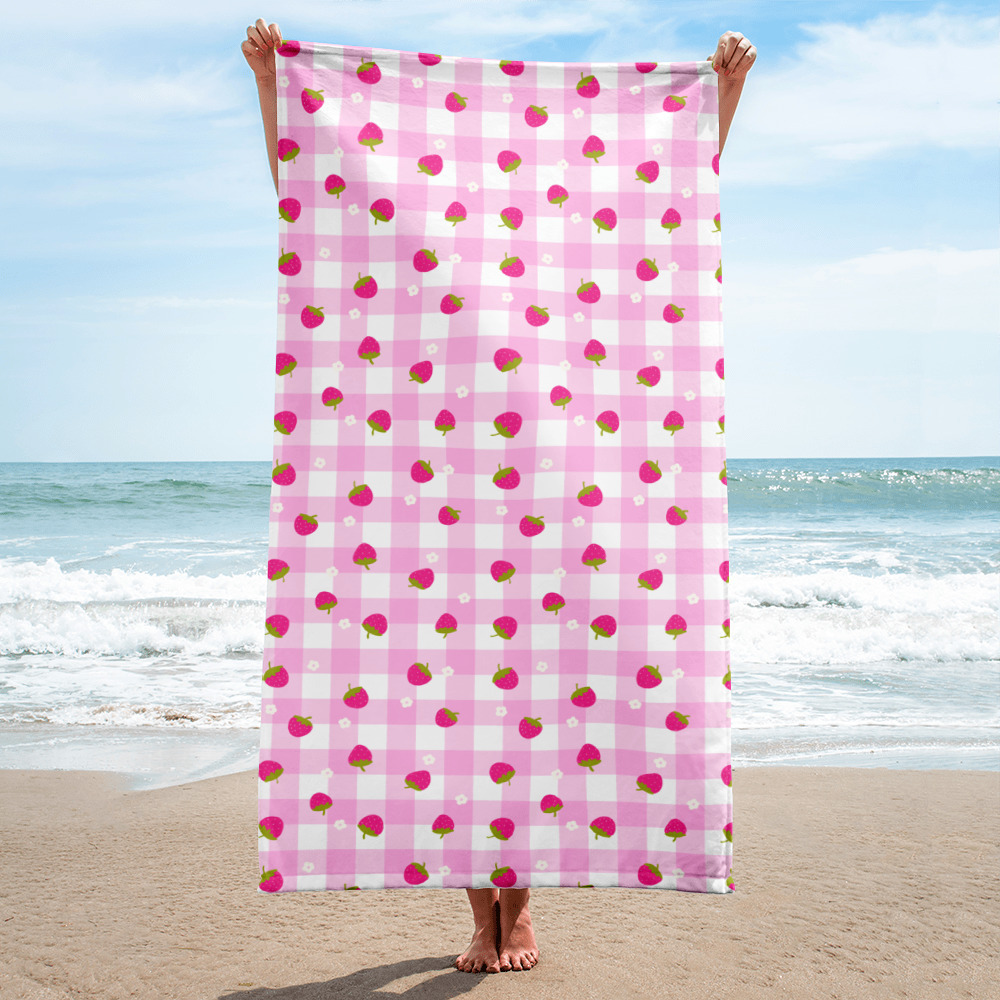 Pink gingham beach towel with cute strawberry ditsy pattern featuring small red berries scattered across checkered background