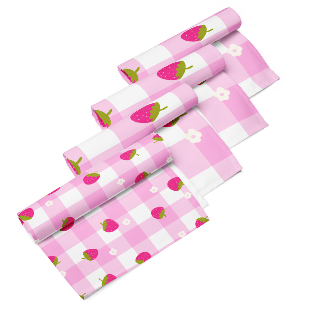 Set of four cloth napkins featuring strawberry ditsy pattern on pink gingham background with white reverse side